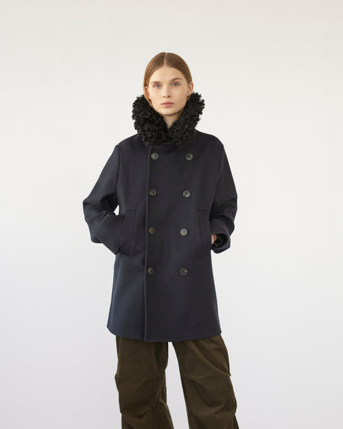 Model wearing a navy Peacoat with a black sheep collar on a white background