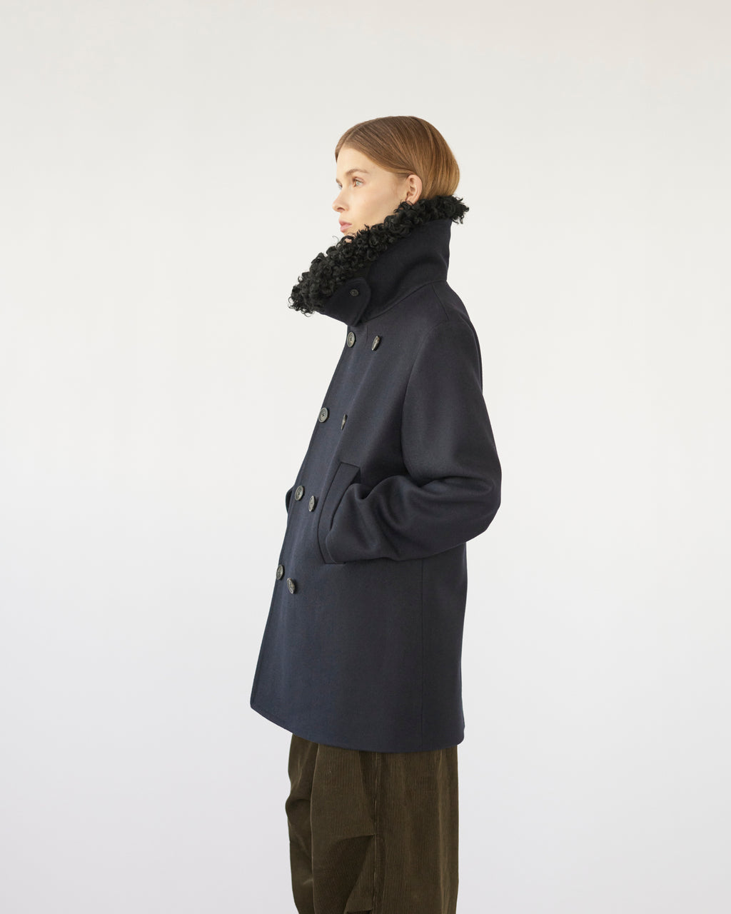 Model wearing a navy Peacoat with a black sheep collar on a white background