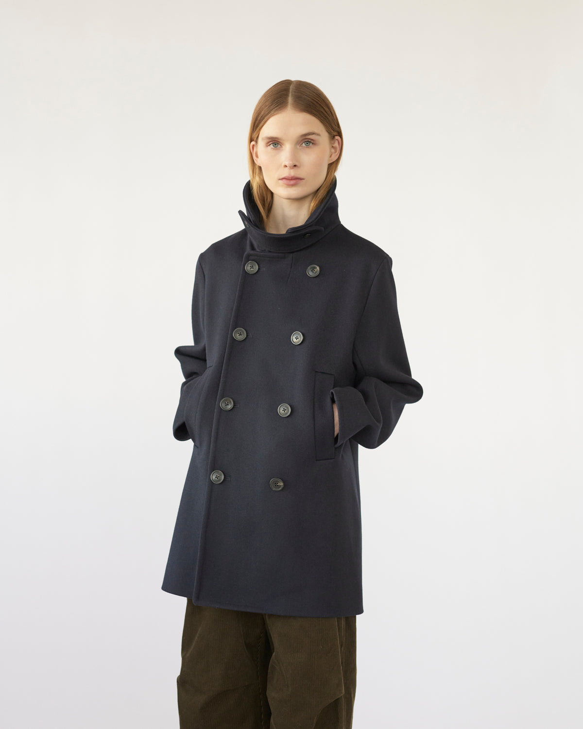 Person wearing a navy coat on a white background