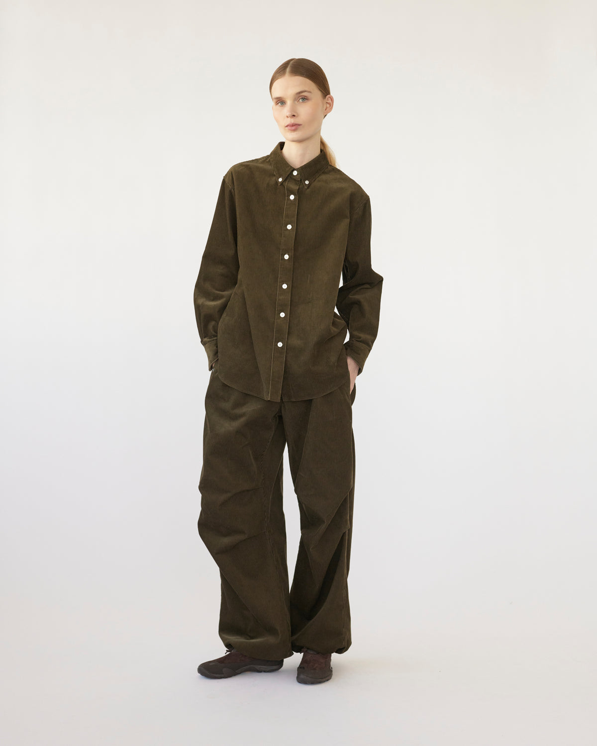 Model wearing a olive corduroy outfit on a white background. Front view