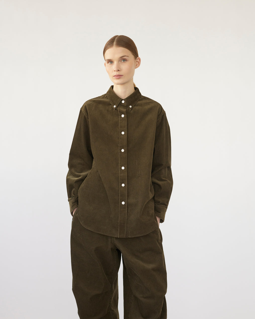 Model wearing a olive corduroy shirt and pants on a white background. Front view
