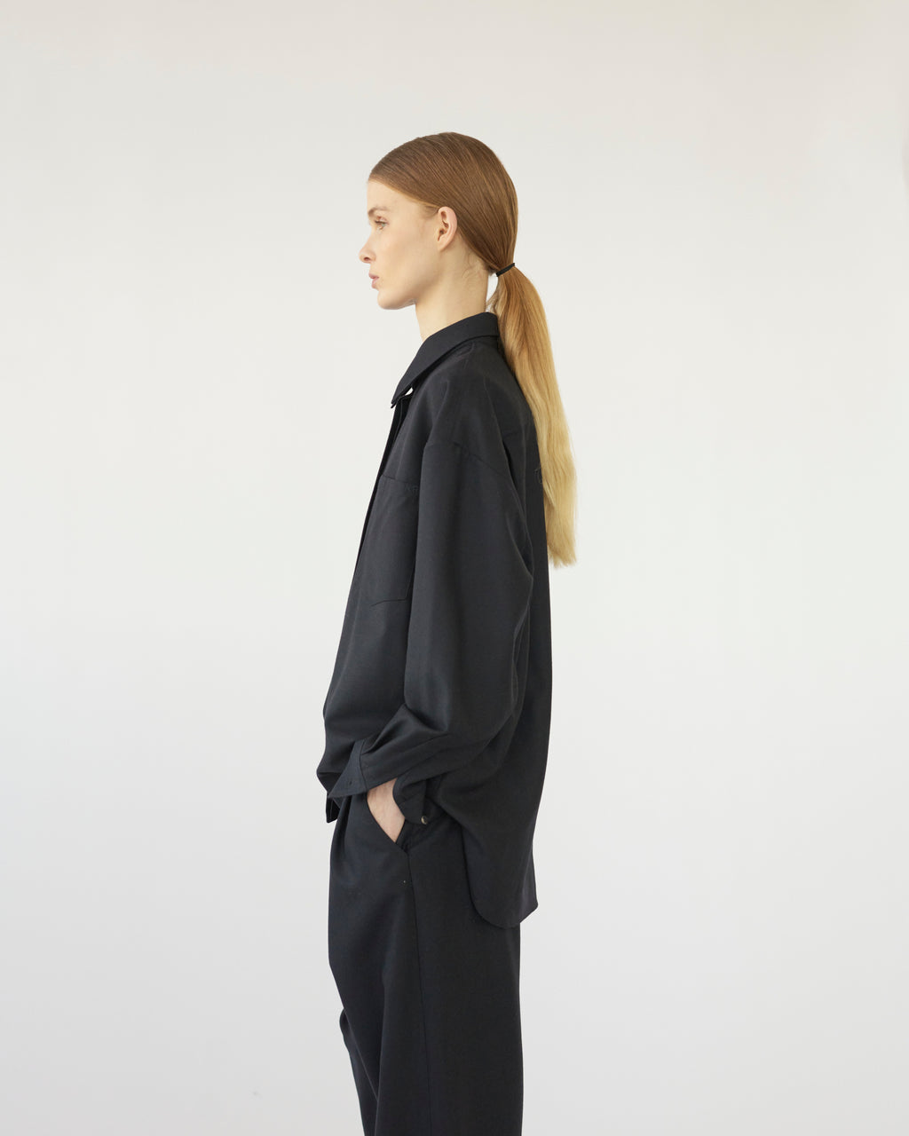 Model wearing a black outfit against a white background. Side view