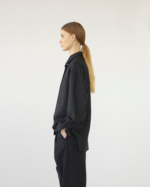 Model wearing a black outfit against a white background. Side view