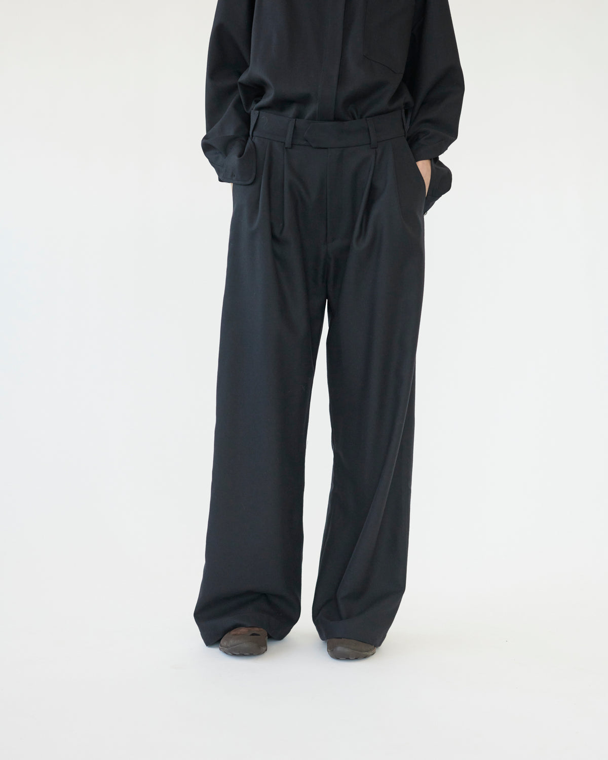Model wearing navy wide-leg pants on a white background