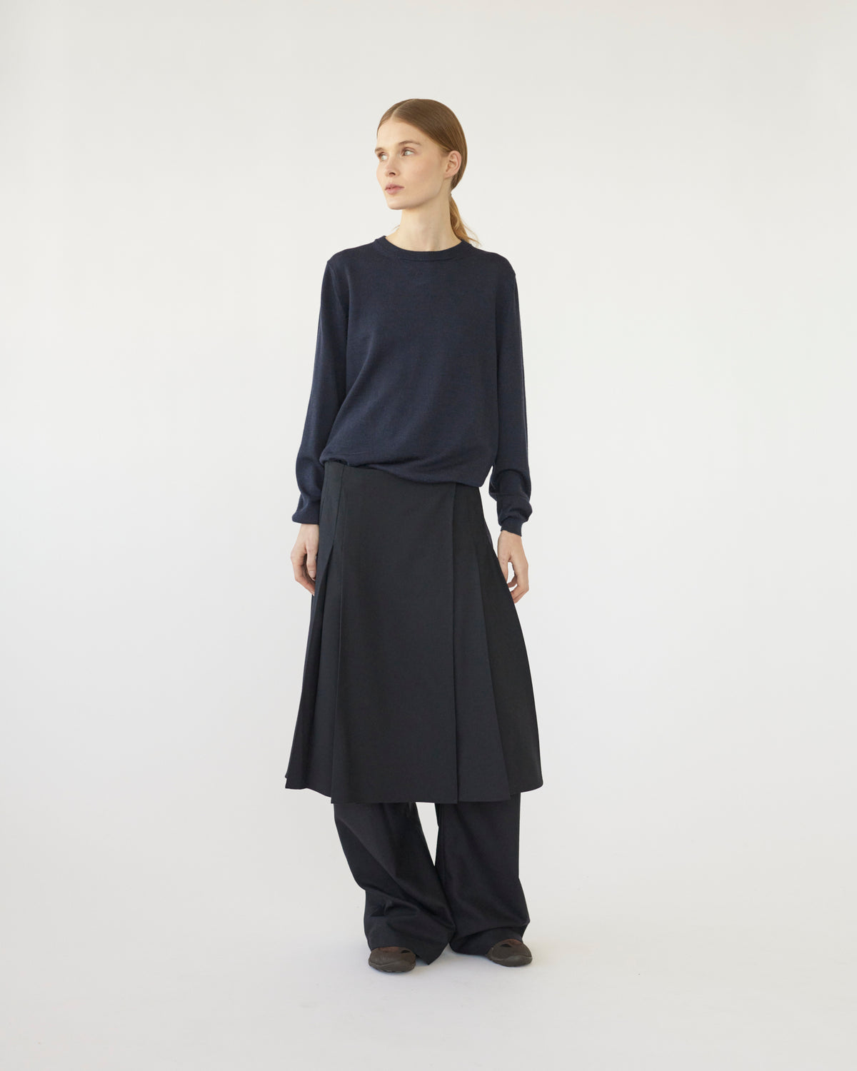 Model wearing a dark blue sweater and Navy skirt on a white background Front view