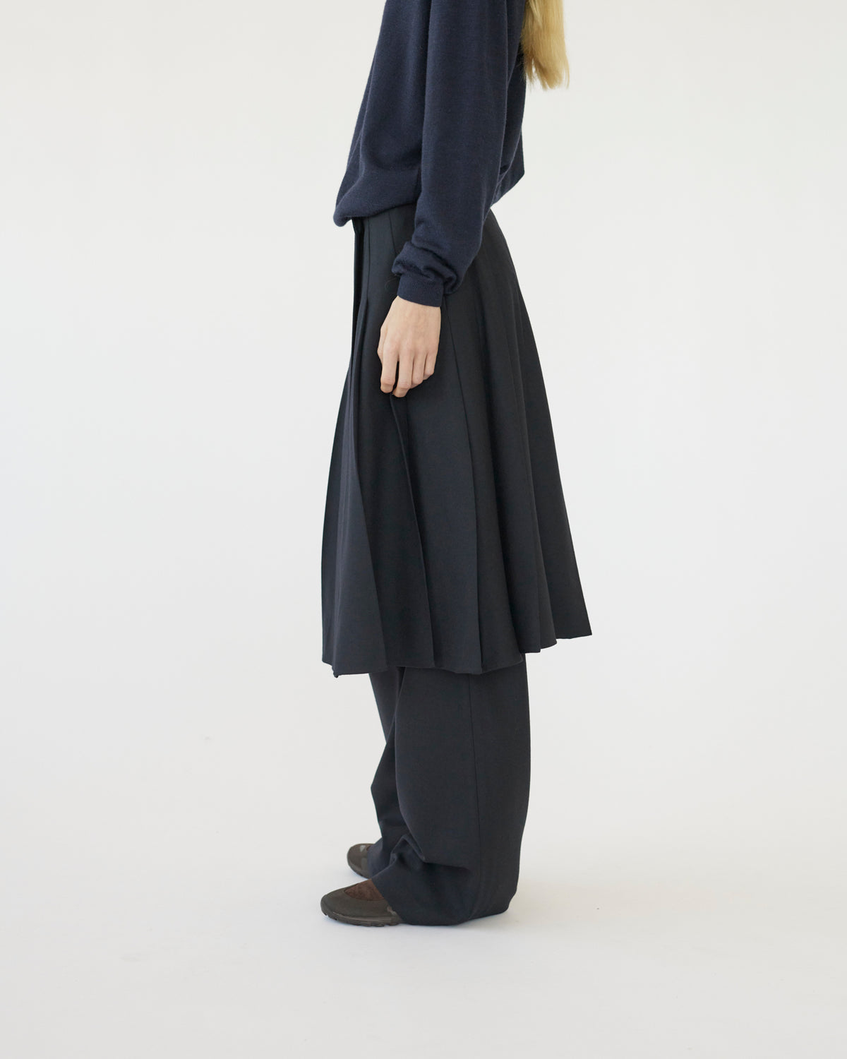 Model wearing a dark blue outfit with a long skirt and top on a white background side view
