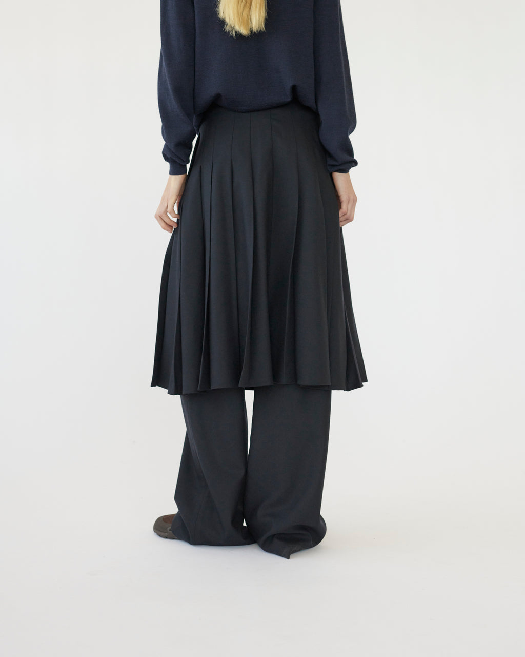 Model wearing a navy skirt and pants on a white background