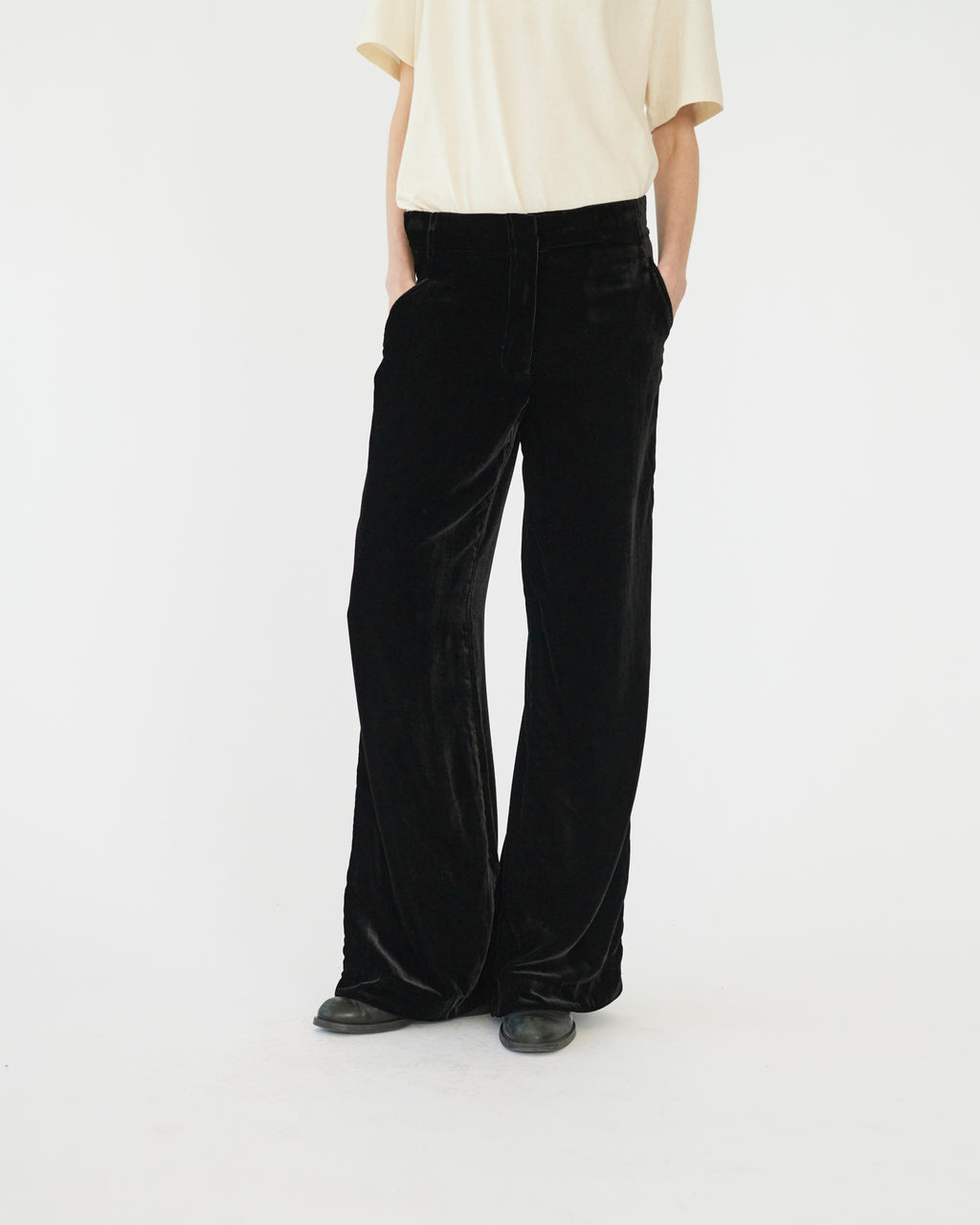 Model wearing black silk velvet pants on a white background. Front view