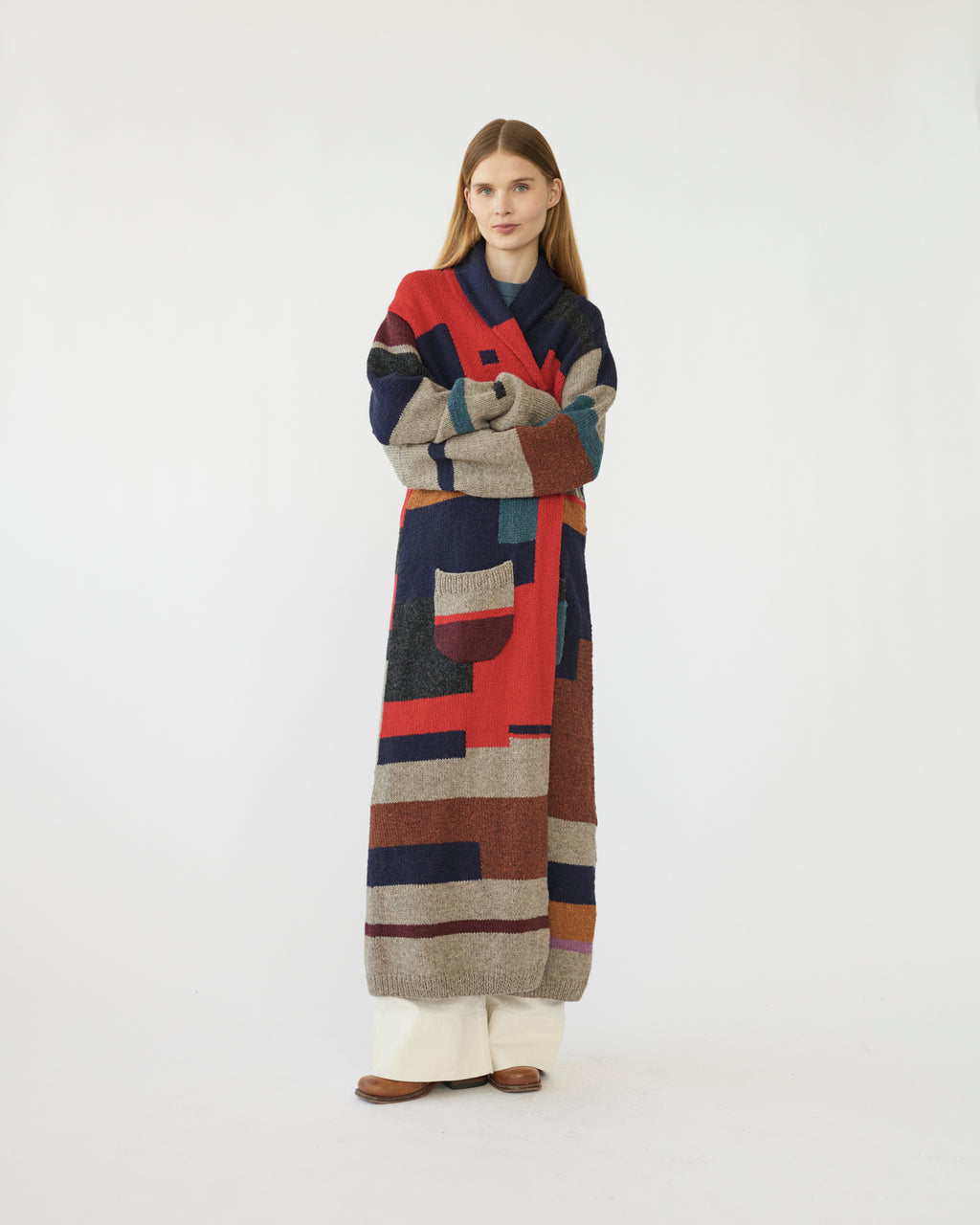 Model wearing a long, multicolored patterned cardigan on a white background