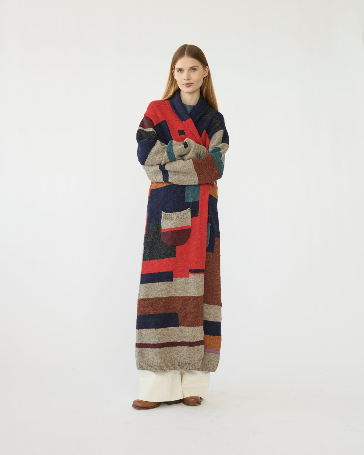 Model wearing a long, multicolored patterned cardigan on a white background
