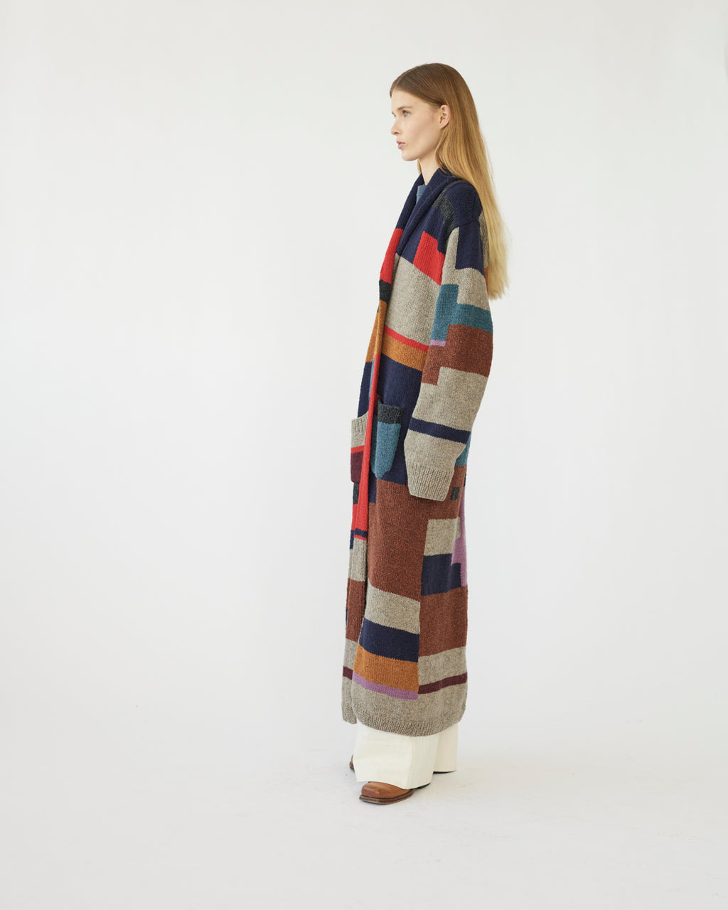 Model wearing a long, multicolored cardigan on a white background