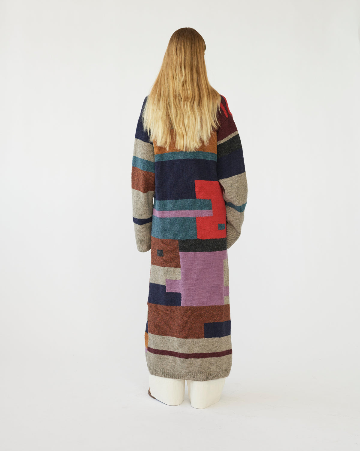 Model wearing a long, multicolored cardigan on a white background