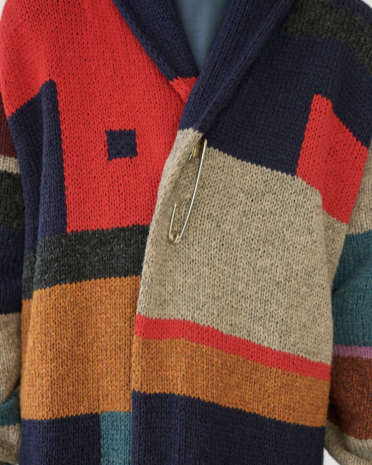 Colorful patterned cardigan with a metal clip on a neutral background