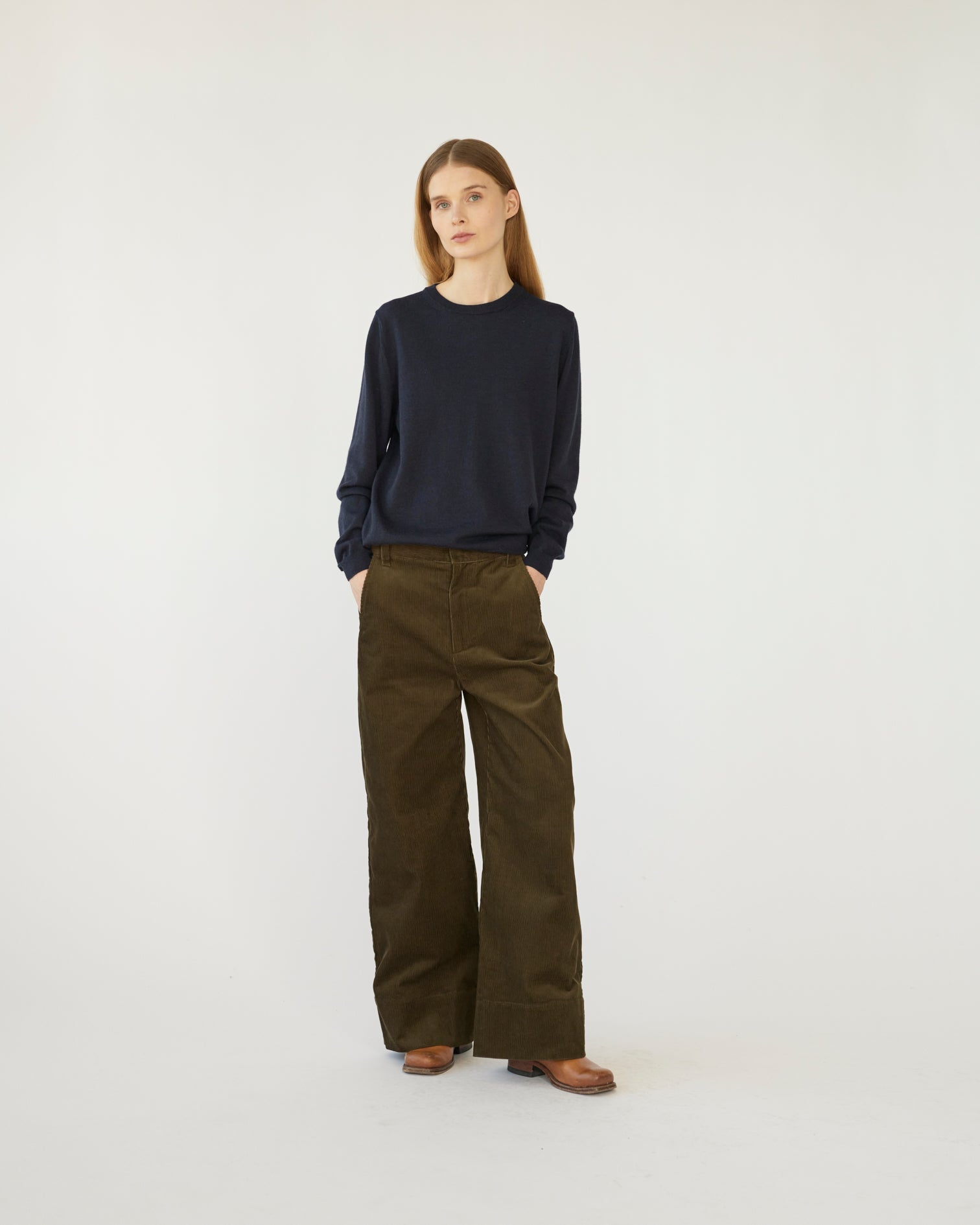 The model is wearing a pair of olive-colored corduroy trousers against a white background front view.