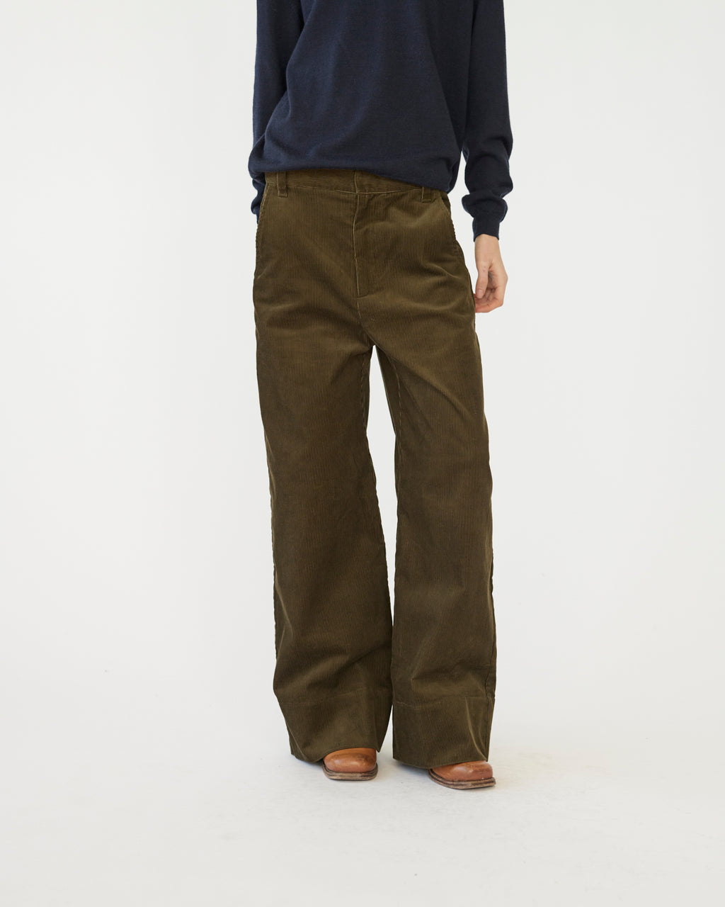 The model is wearing a pair of olive-colored corduroy trousers against a white background.