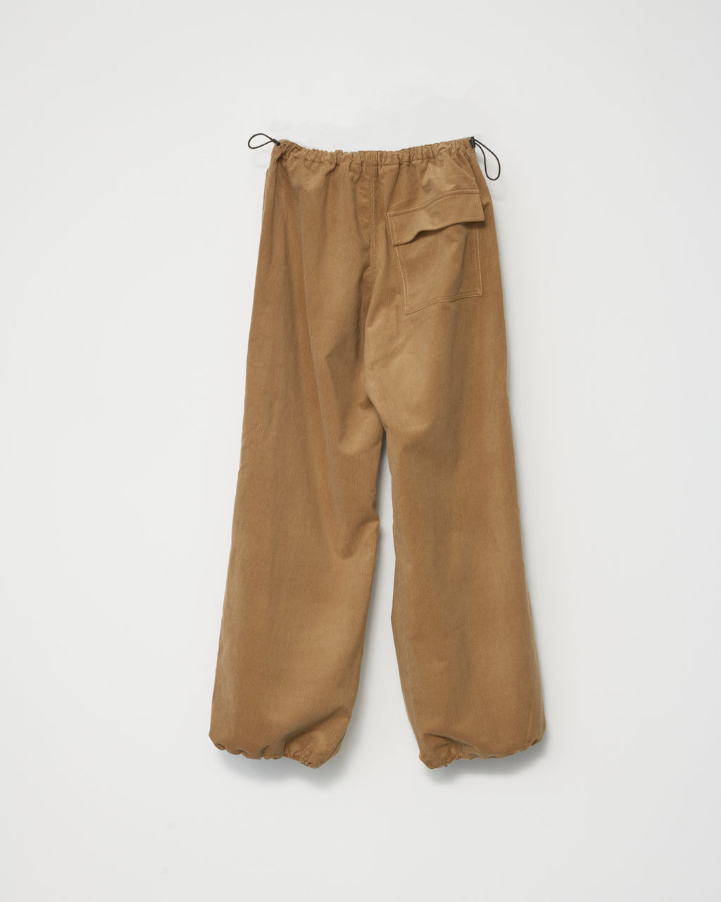  a pair of wide-leg corduroy trousers in tobacco with an adjustable elastic waistband. White background, back view.