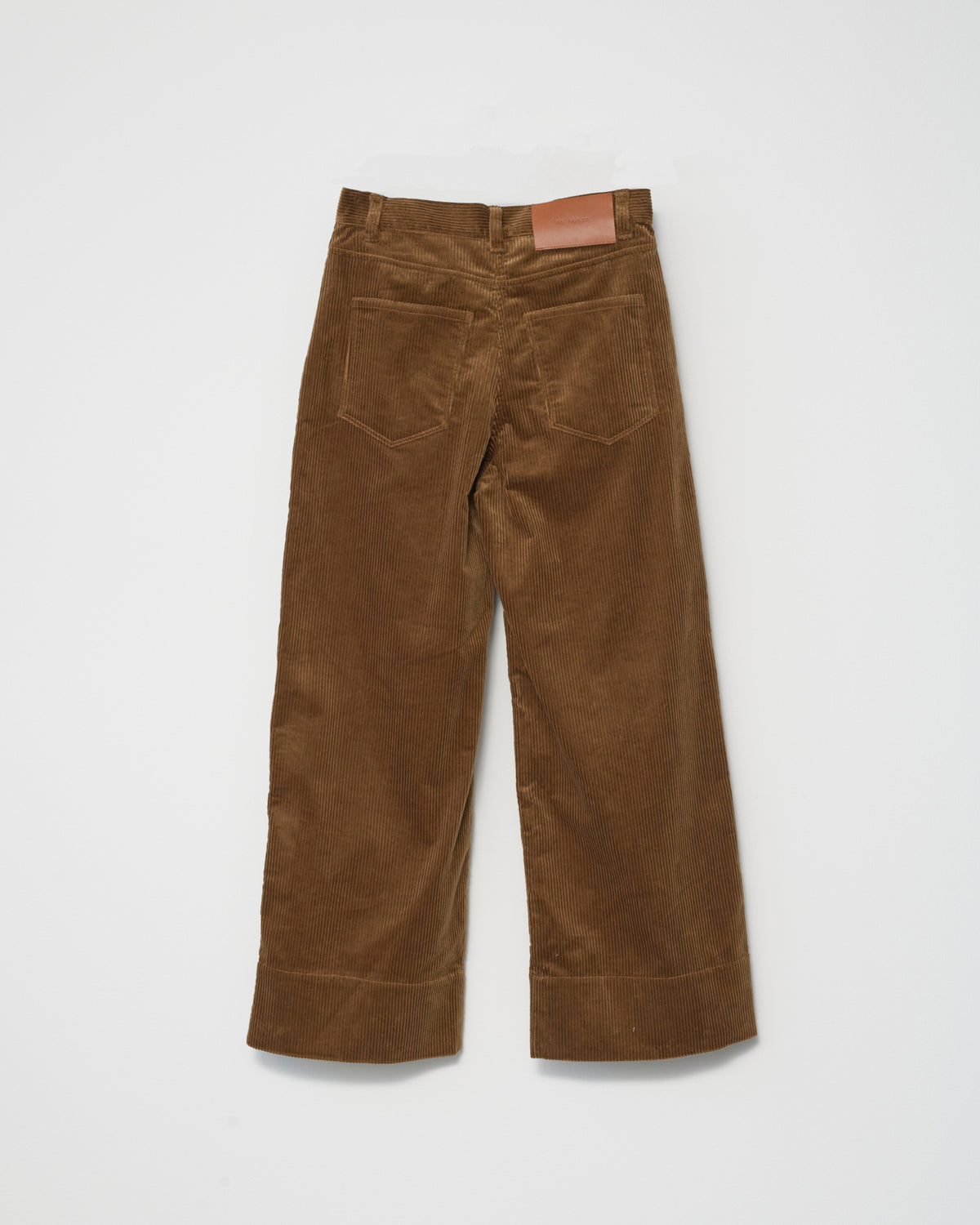 A pair of cognac-colored corduroy trousers against a white background back  view.