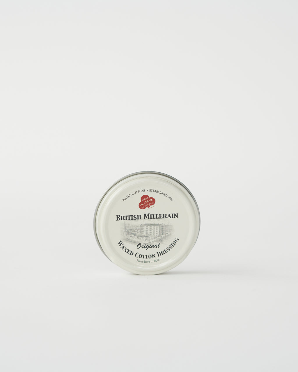 A tin container of British Millerain waxed cotton dressing with a label that includes the brand name and product details.