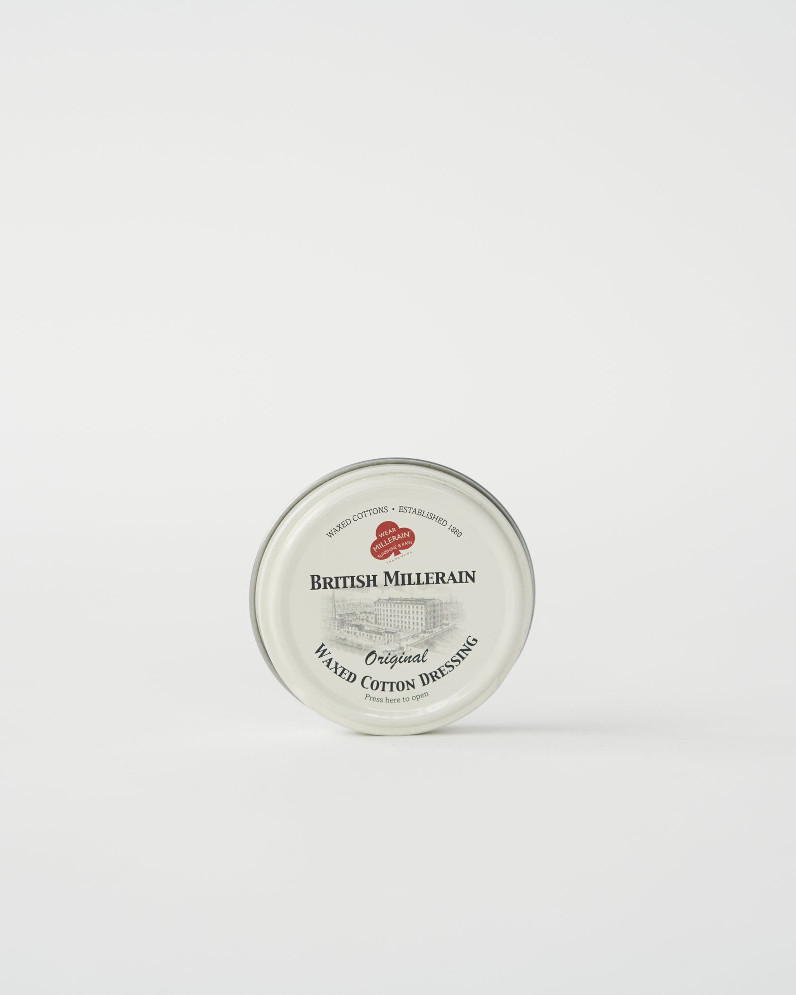 A tin container of British Millerain waxed cotton dressing with a label that includes the brand name and product details.