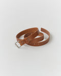 A narrow brown leather belt with a metal buckle, displayed on a white background.